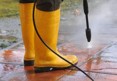 persona-vestida-botas-goma-amarilla-boquilla-agua-alta-presion-limpiando-suciedad-baldosas